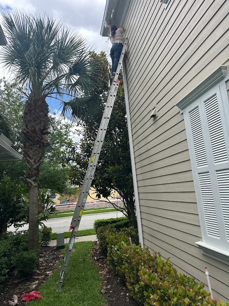 A Swift Wildlife technician on a ladder sealing a Treasure Coast home's eave and soffit — humane bat exclusion